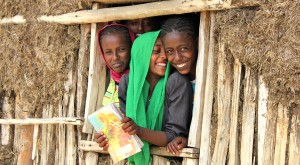 Några flickor står och tittar ut genom fönstret och skrattar i Etiopien