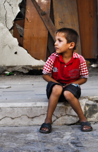 En pojke sitter på en smutsig gata