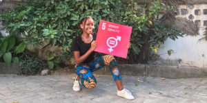 Jennifer i Tanzania håller upp en skylt för mål 5 inom de globala målen. Foto: Jane-Ange Musekura
