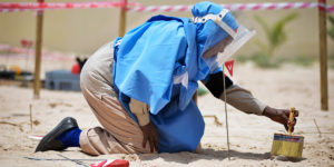 En kvinnlig medarbetare sopar bort sand från en explosiv lämning under en träningsdag i Somalia. Foto: UN Photo/Tobin Jones