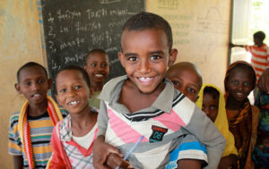 Abera och Teddo tillsammans med flera barn i en skola som får skolmat genom Projekt Skolmat
