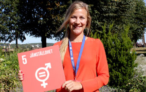 Ambassadören Mikaela håller upp en skylt för jämställdhet och de globala målen