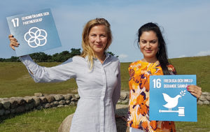 Mikaela och Sara håller upp skyltar för de globala målen för hållbar utveckling