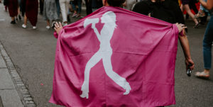Under en protest håller någon upp en rosa flagga med en illustration av någon som ropar i en megafon