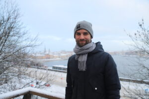 David Collste står och ler in i kameran med ett snöigt Stockholm bakom sig