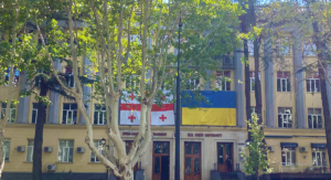 Georgiens och Ukrainas flagga händer bredvid varandra på en byggnad med träd framför