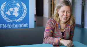 Läraren Jessica Rundquist på Nyköpings gymnasium. Sitter vid ett bord med FN-logga bakom sig.