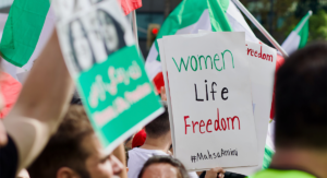 En skylt med texten "women, life,freedom" hålls upp av personer som protesterar mot förtrycket av kvinnor i Iran.
