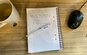 En kopp te, ett anteckningsblock, en penna och en datormus på ett skrivbord
