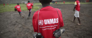 En pojke står med ryggen till i en röd T-shirt med texten Unmas i vitt.